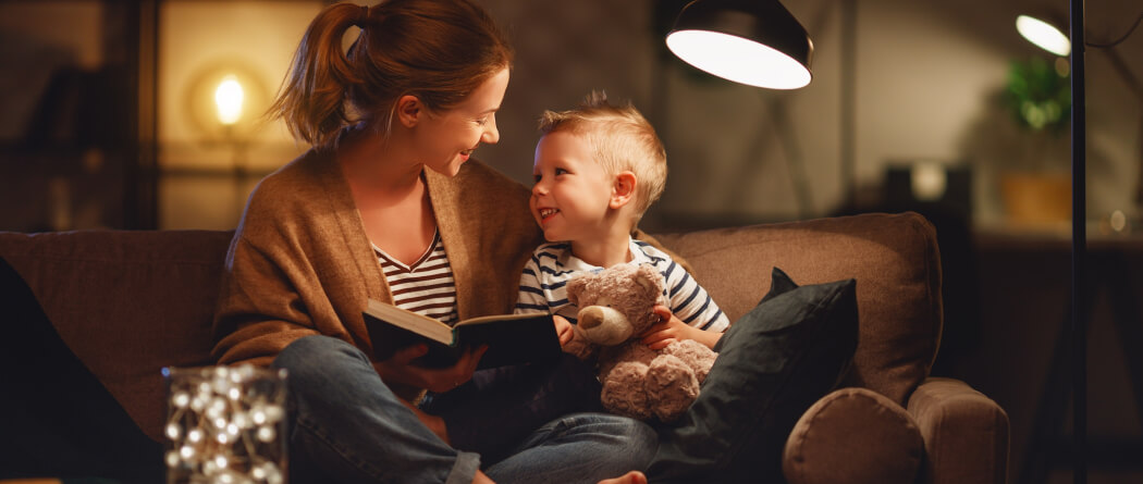 Young mom and child reading a book under a lamp 
